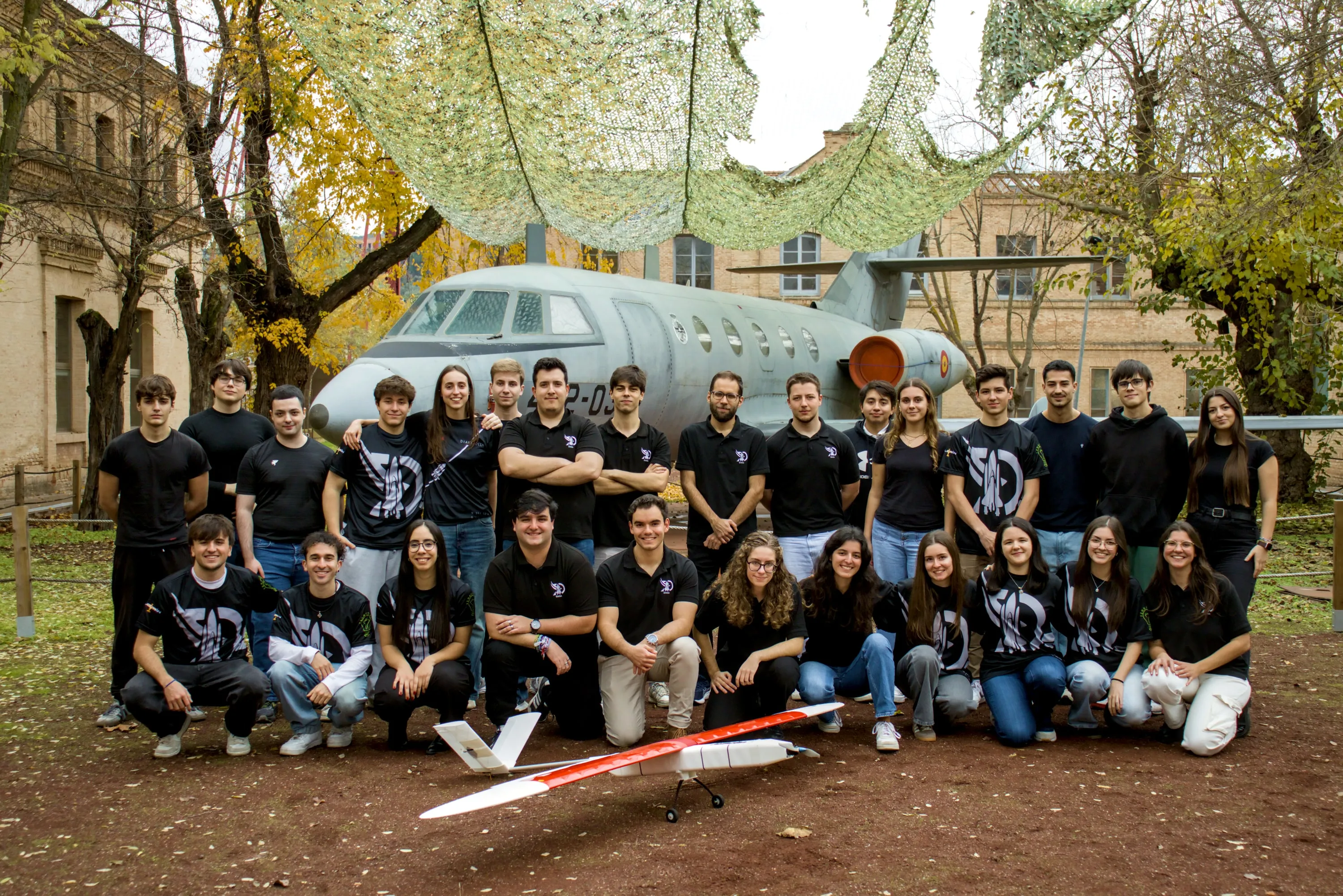 El equipo de DIANA posa con el Aurora delante de un avión de exposición en el campus de la Fábrica de Armas de Toledo
